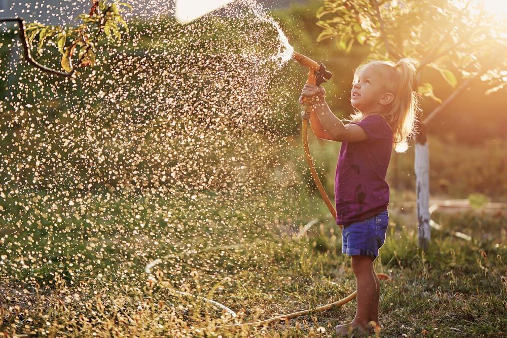 Child using a hose on a sunny day