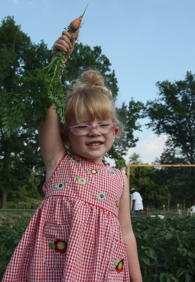 Child holding up baby carrots